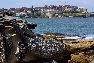 Close-up of sea by cityscape against sky