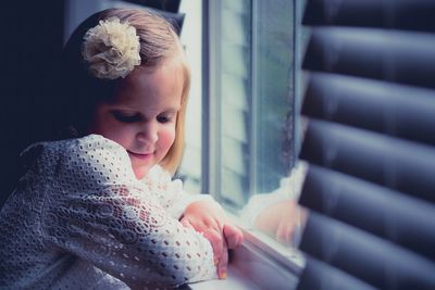 Thoughtful smiling girl by window at home