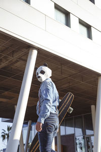 Hipster with panda bear mask and longboard
