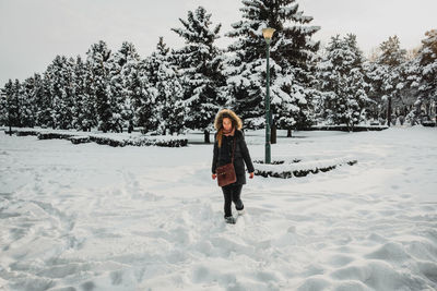 Full length portrait of woman on snow covered field