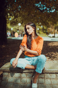 Full length of a young woman sitting outdoors