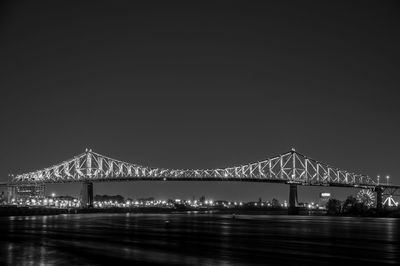Illuminated bridge over river against sky at night