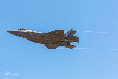 Low angle view of airplane flying against clear blue sky