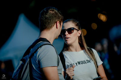 Young man and woman wearing sunglasses standing outdoors