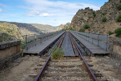 Railroad tracks leading towards mountain against sky