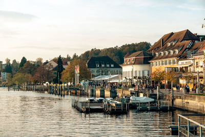 Buildings by river against sky