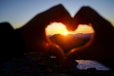 Close-up of silhouette heart shape on rock against sky during sunset