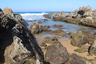 Scenic view of rocks in sea against clear sky