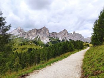 Road amidst trees against mountains and sky