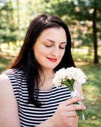 Beautiful young woman holding red flowering plant