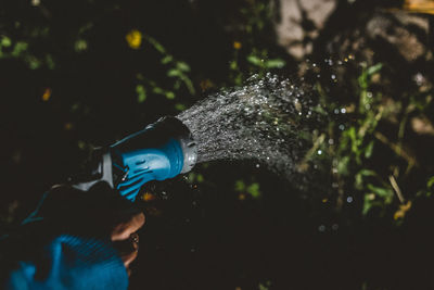 Close-up of person watering plants at night