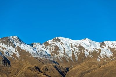 Scenic view of snowcapped mountains against clear blue sky