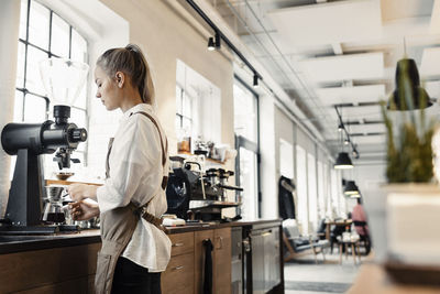 Side view of barista preparing coffee at counter at cafe