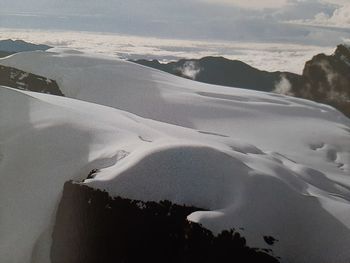 Scenic view of sea by snowcapped mountain against sky