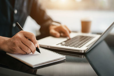 Midsection of man using laptop on table