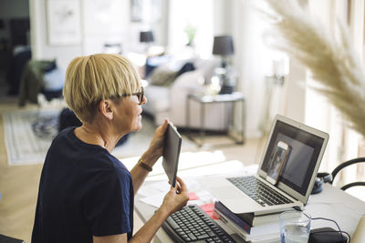 Woman working at home showing digital screen to coworker