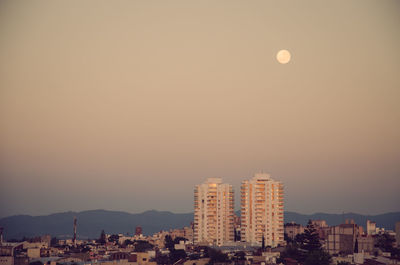 Buildings in city against clear sky during sunset