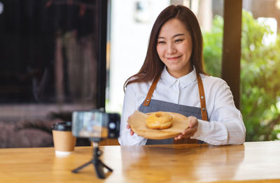 Portrait of young woman using mobile phone while sitting on table