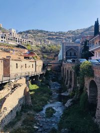 Arch bridge over canal amidst buildings against clear sky