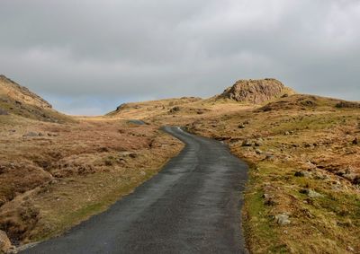 Empty road leading towards mountain against sky