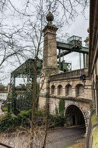 Bare trees against sky in city