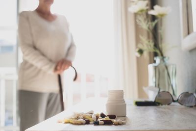 Midsection of woman standing by table at home