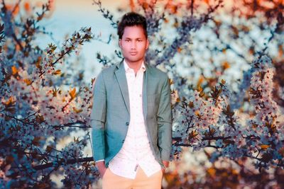 Portrait of young man standing against plants