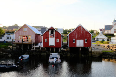 Houses by river amidst buildings against sky