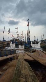 Sailboats moored at harbor against sky