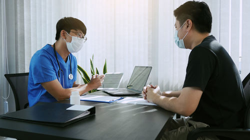 Business persons wearing mask sitting at office