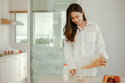 Young woman holding ice cream at home