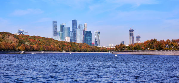 River by modern buildings against sky in city