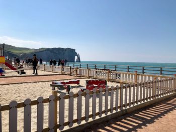 People on beach against clear blue sky