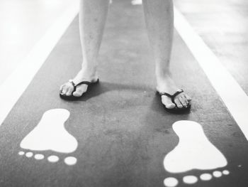 Low section of man standing by footprint sign on footpath