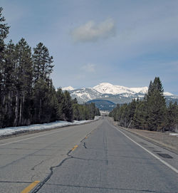 Road by trees and mountains against sky