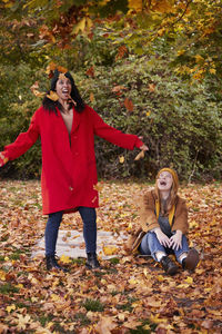 Friends playing with autumn leaves in park