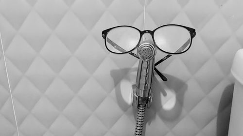 Close-up of eyeglasses on hose in bathroom