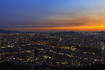 High angle view of illuminated city against sky at sunset