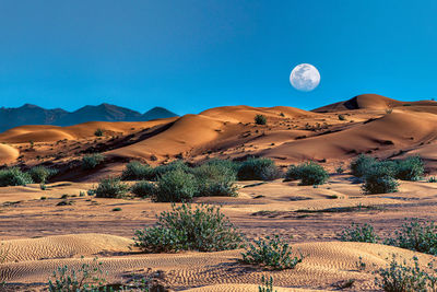 Scenic view of desert against clear blue sky