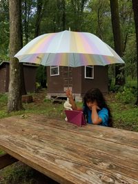 Rear view of woman sitting on chair against trees