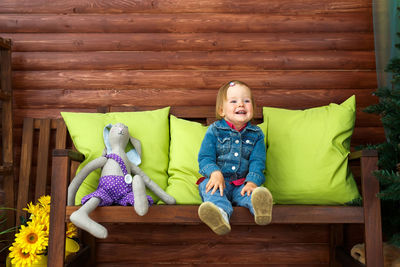 Portrait of cute boy sitting on wood at home