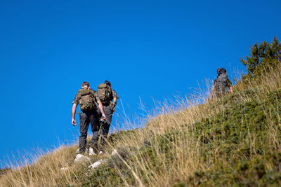 Hikers with backpacks on their shoulders walk up the mountain. blue sky in the background.