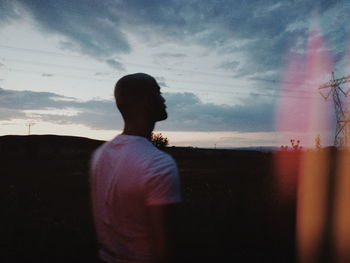 REAR VIEW OF MAN LOOKING AT SUNSET