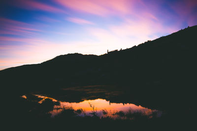 Scenic view of silhouette mountains against orange sky