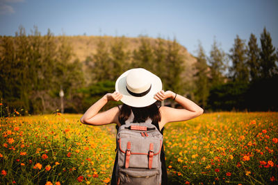 Rear view of woman wearing hat standing on field