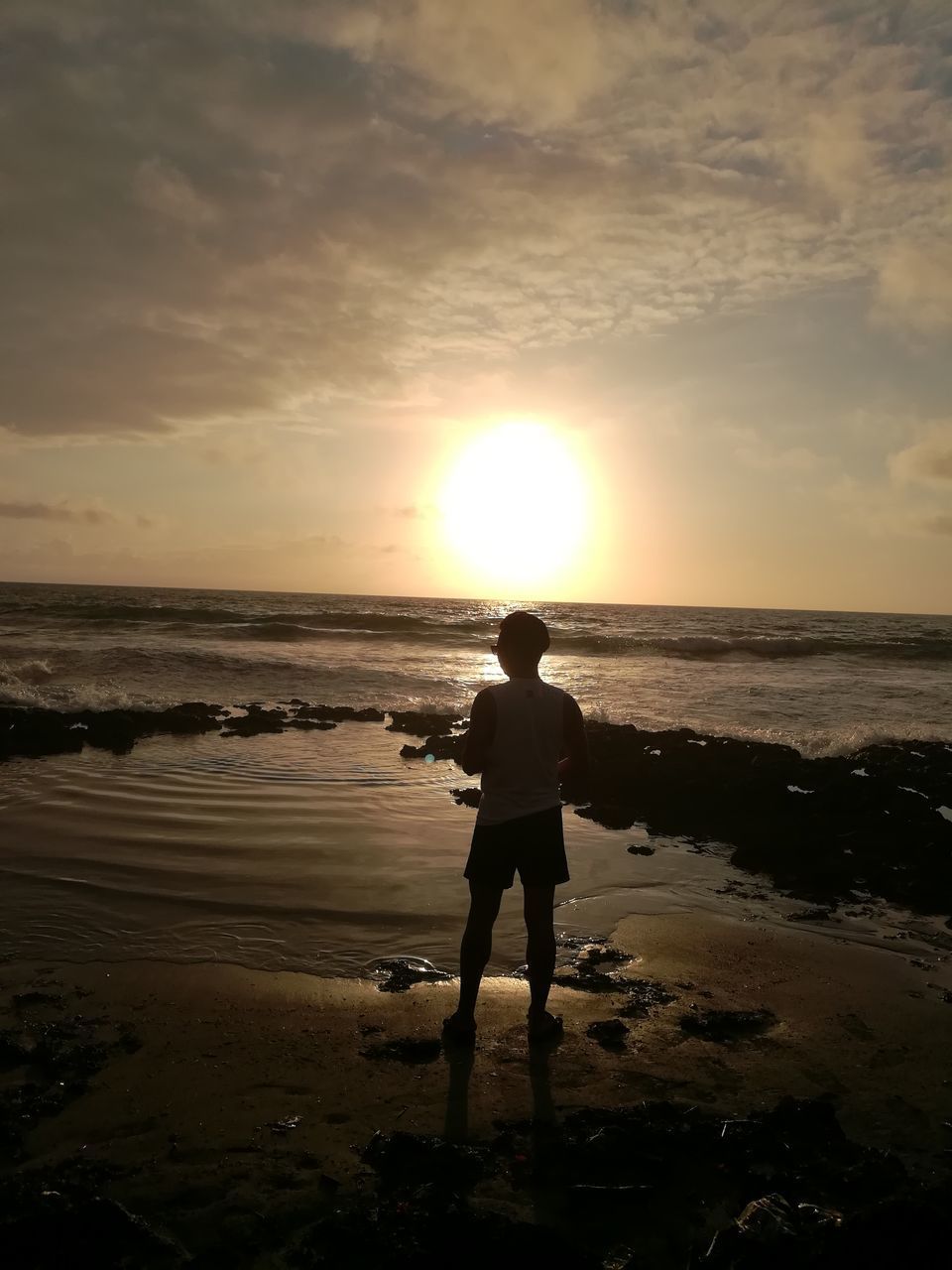 REAR VIEW OF SILHOUETTE MAN STANDING AT BEACH AGAINST SKY