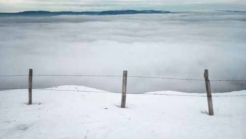 Snow covered landscape by sea against sky