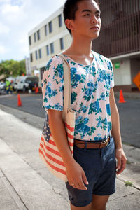 Young man standing on sidewalk in city