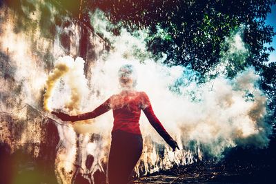 Woman holding distress flare against trees