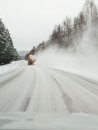 Car on snow covered road against sky